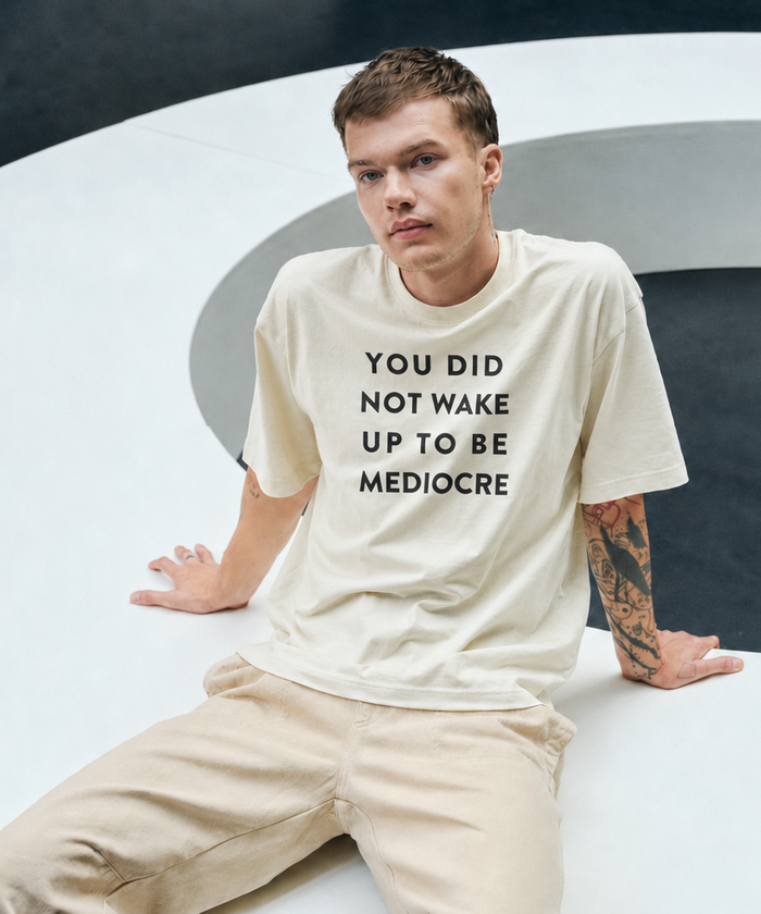 Person wearing a white t-shirt with text, sitting on a modern white chair.